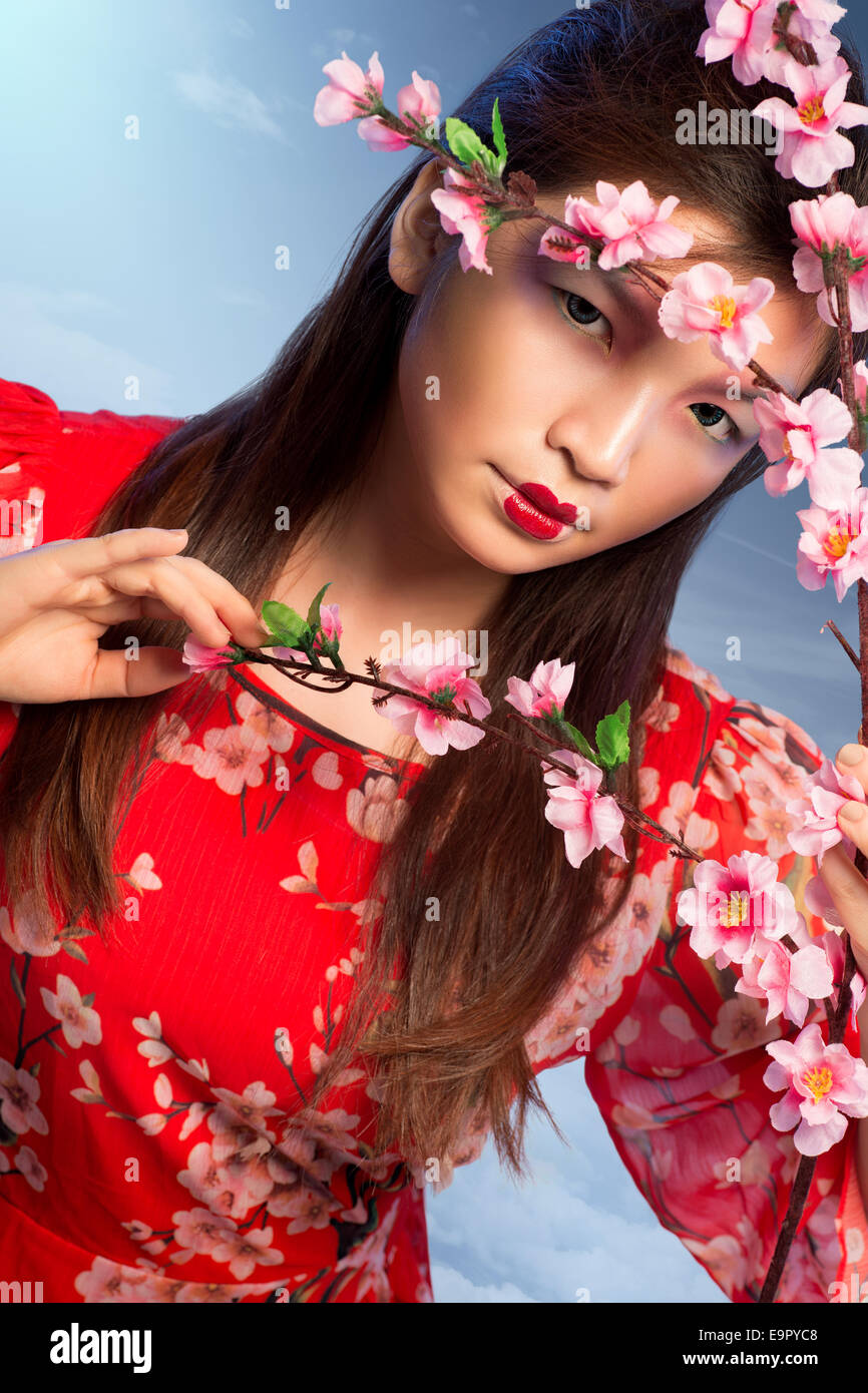 Schöne Frau im roten Kleid mit blühenden Pfirsich Baum Stockfoto