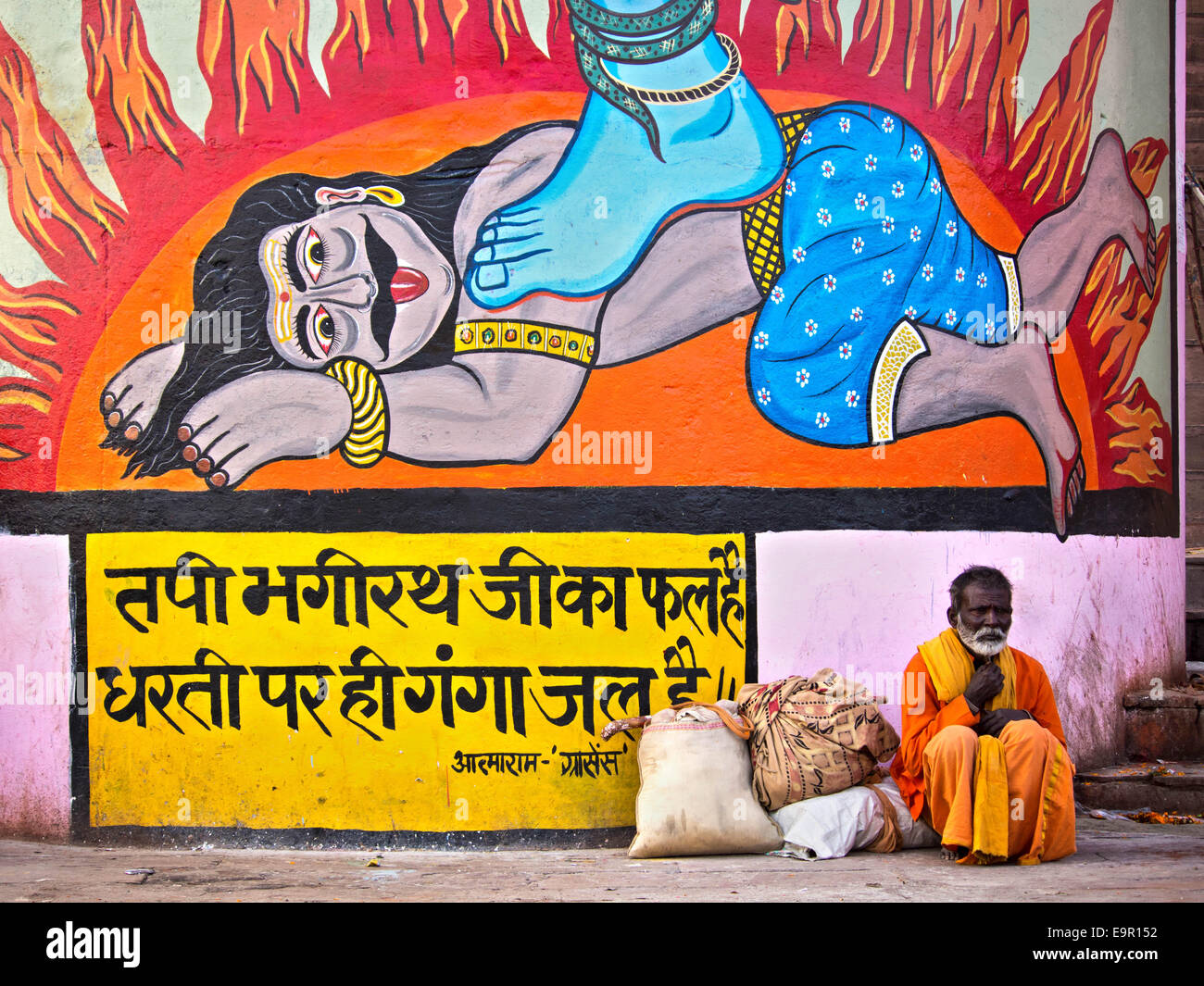 Indischer Mann sitzt vor bunten Streetart Wandbild in Varanasi, Uttar Pradesh, Indien. Stockfoto