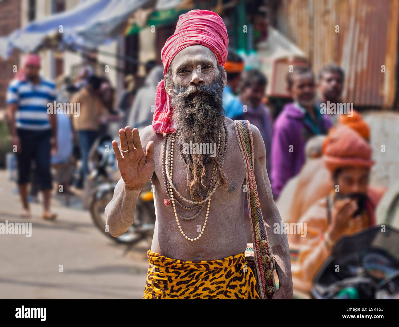 Porträt eines Sadhu (indischer heiliger Mann) in Asche bedeckt und tragen bunte Kleidung auf einer belebten Straße in Varanasi, Indien. Stockfoto