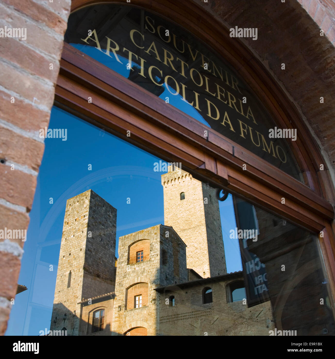 San Gimignano, Toskana, Italien. Mittelalterliche Türme spiegelt sich im Fenster ein Souvenir-Shop in Piazza della Cisterna. Stockfoto