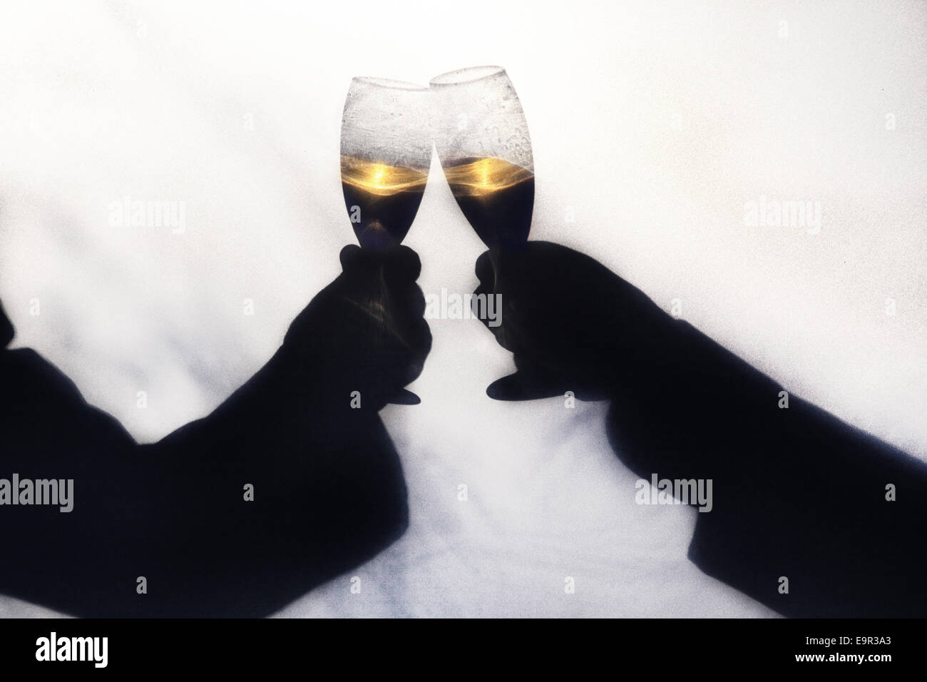Zwei schwule Männer, die ihre Hochzeit mit Champagner zu toasten.  Silhoette genommen im Freien hinter einer Leinwand mit abstrakten Formen der Bäume und Stockfoto