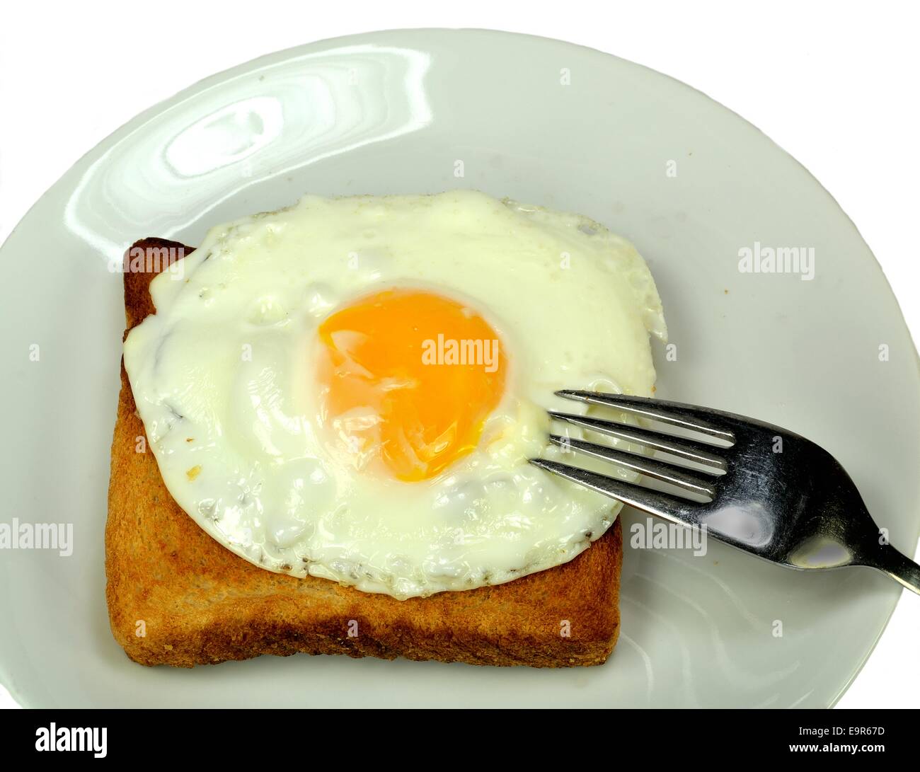 Gebratenes Ei auf Toast mit einer Gabel einstechen. Stockfoto