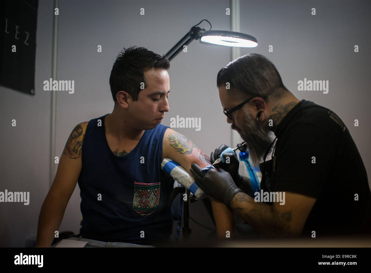 Mexico City, Mexiko. 31. Oktober 2014. Ein Mann macht eine Tattoo auf dem Arm eines Kunden während der Expo Tattoos Mexiko 2014 in Mexiko-Stadt, Hauptstadt von Mexiko, am 31. Oktober 2014. © Pedro Mera/Xinhua/Alamy Live-Nachrichten Stockfoto