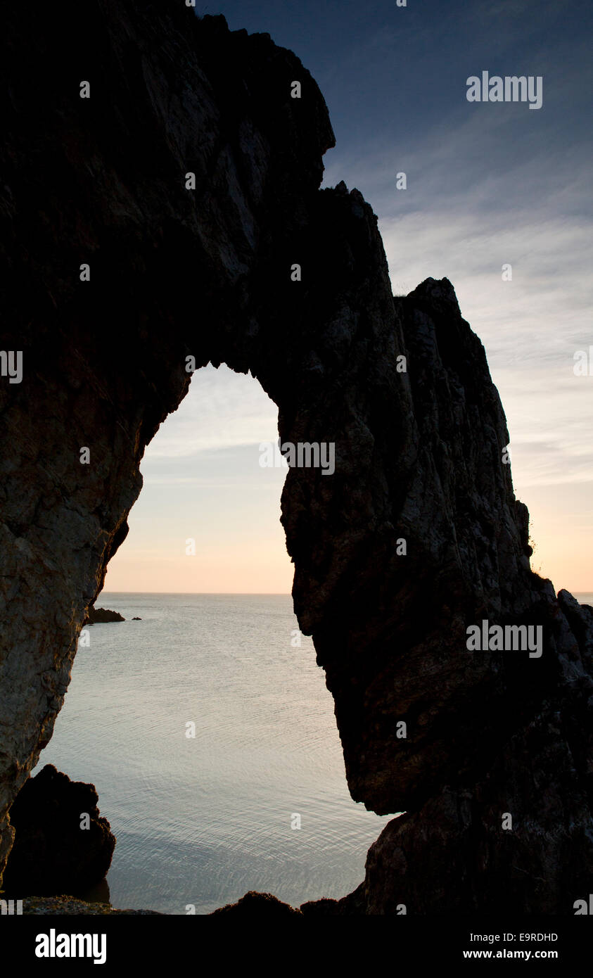 Natürlichen Felsbogen mit Blick aufs Meer um Sonnenaufgang in Porth Wen Bucht an der Nordküste auf Isle of Anglesey, Nordwales Stockfoto