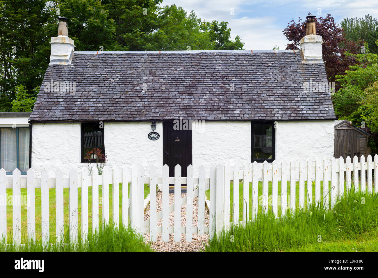 Malerische traditionelle Highland Stein Bungalow Ferienhaus mit weißen Paling Zaun am Port Appin, Argyllshire in den Highlands Scotla Stockfoto