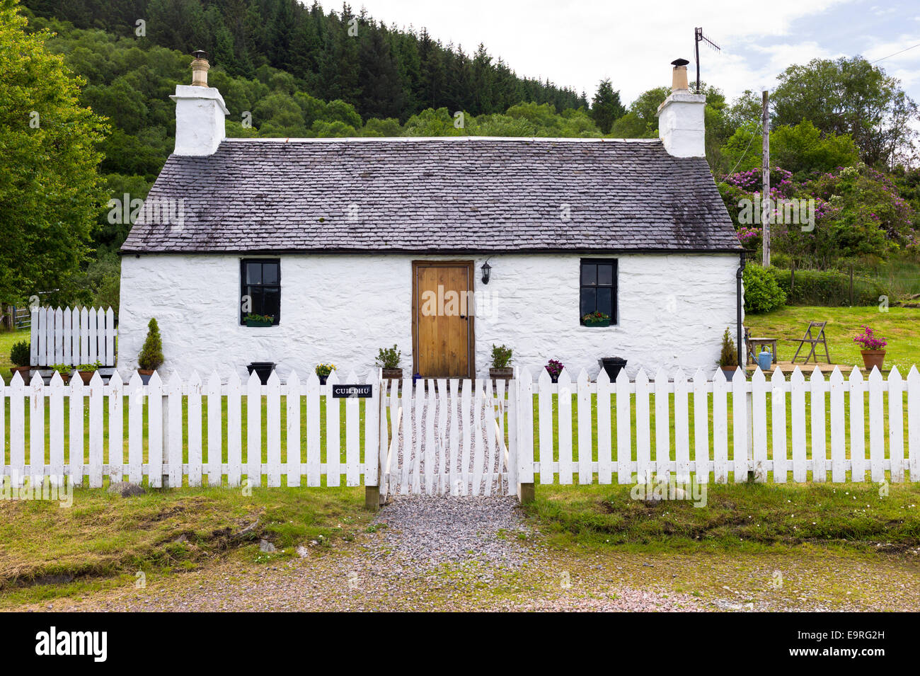 Malerische traditionelle Highland Stein Bungalow Ferienhaus mit weißen Paling Zaun am Appin, Argyllshire in den Highlands von Schottland Stockfoto