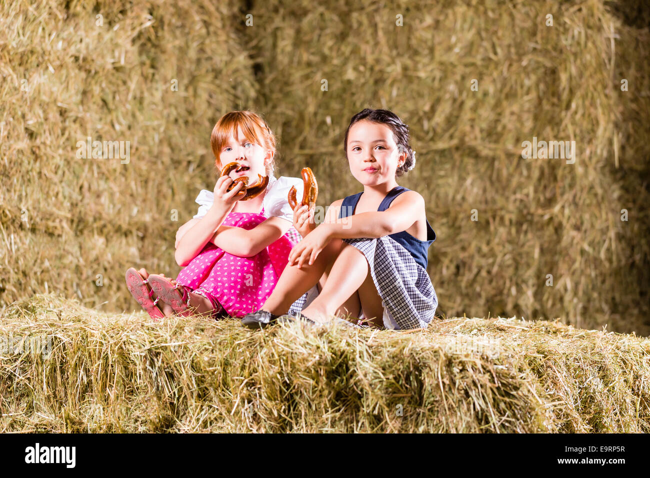 Bayerische Mädchen sitzen auf Heuboden mit Brezeln Stockfoto