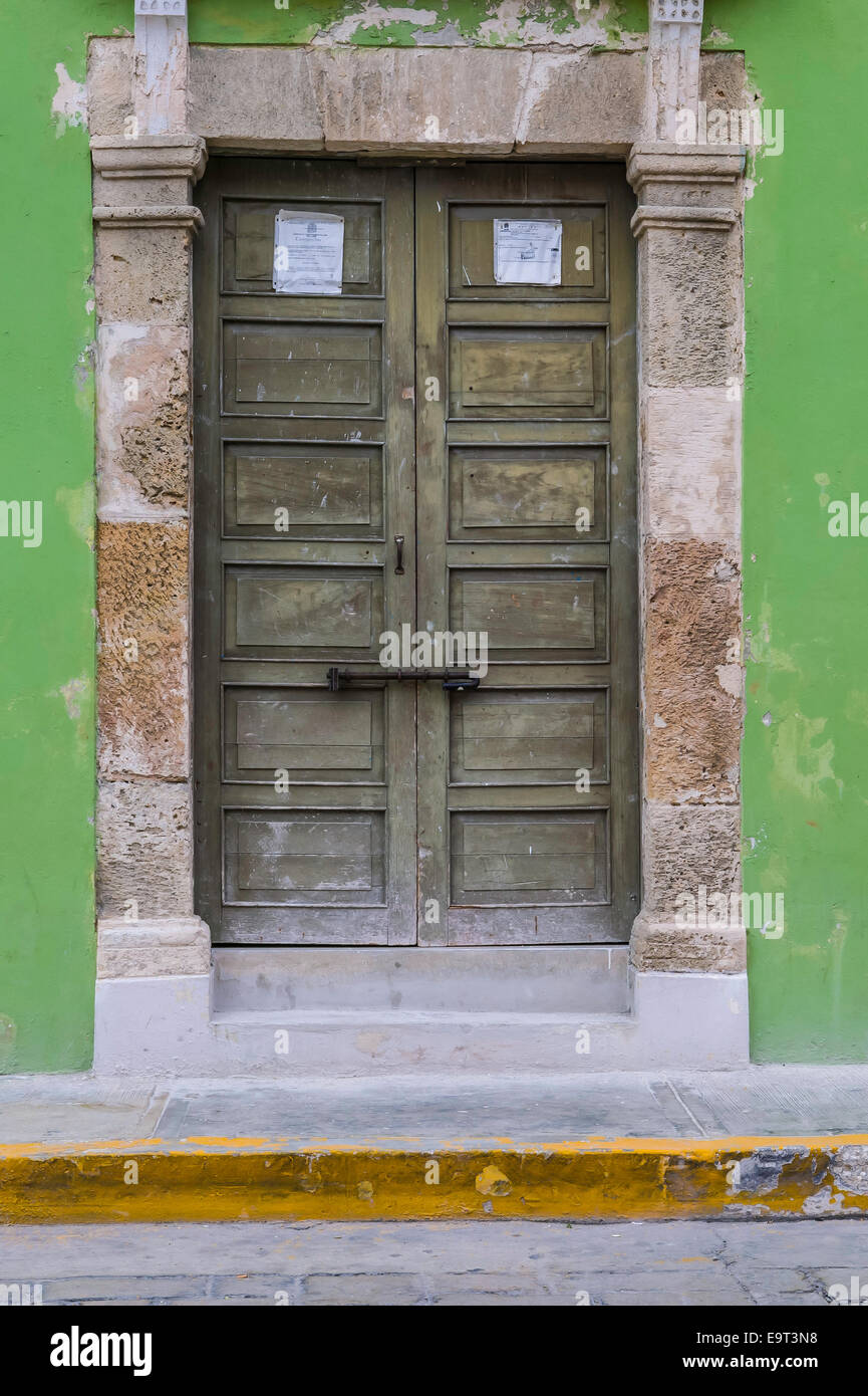 Nahaufnahme eines großen braunen Holztür mit Stein Türverkleidungen auf einem grünen Stuck spanische Haus im Kolonialstil, Campeche, Mexiko Stockfoto