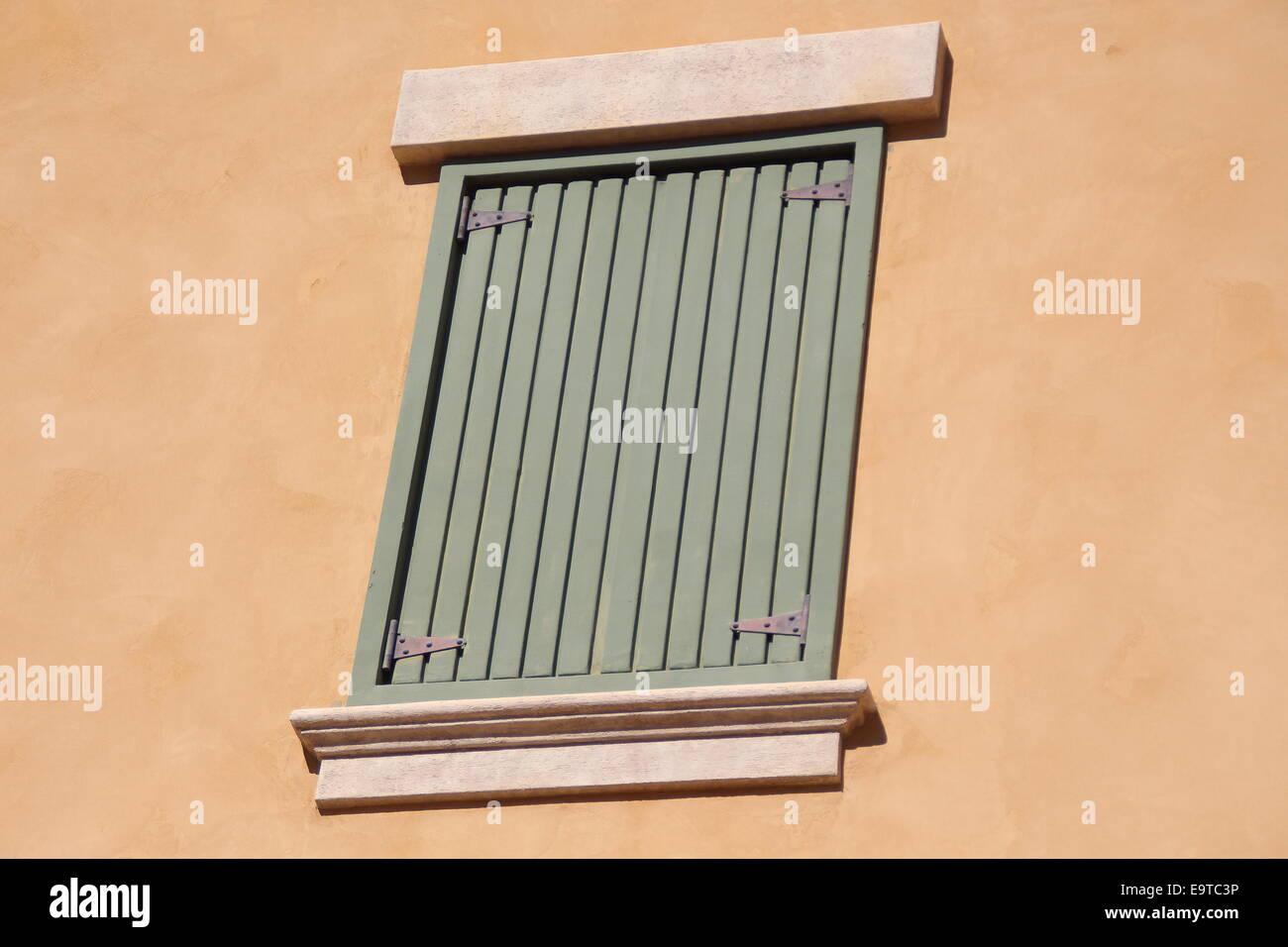 Blasse grüne Schindeln auf einem Tan Gebäude Stockfoto
