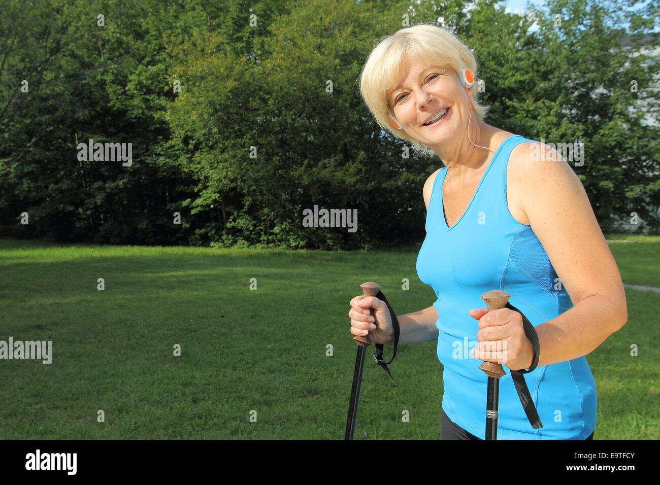 Eine ältere Frau Nordic Walking mit Kopfhörer Stockfoto