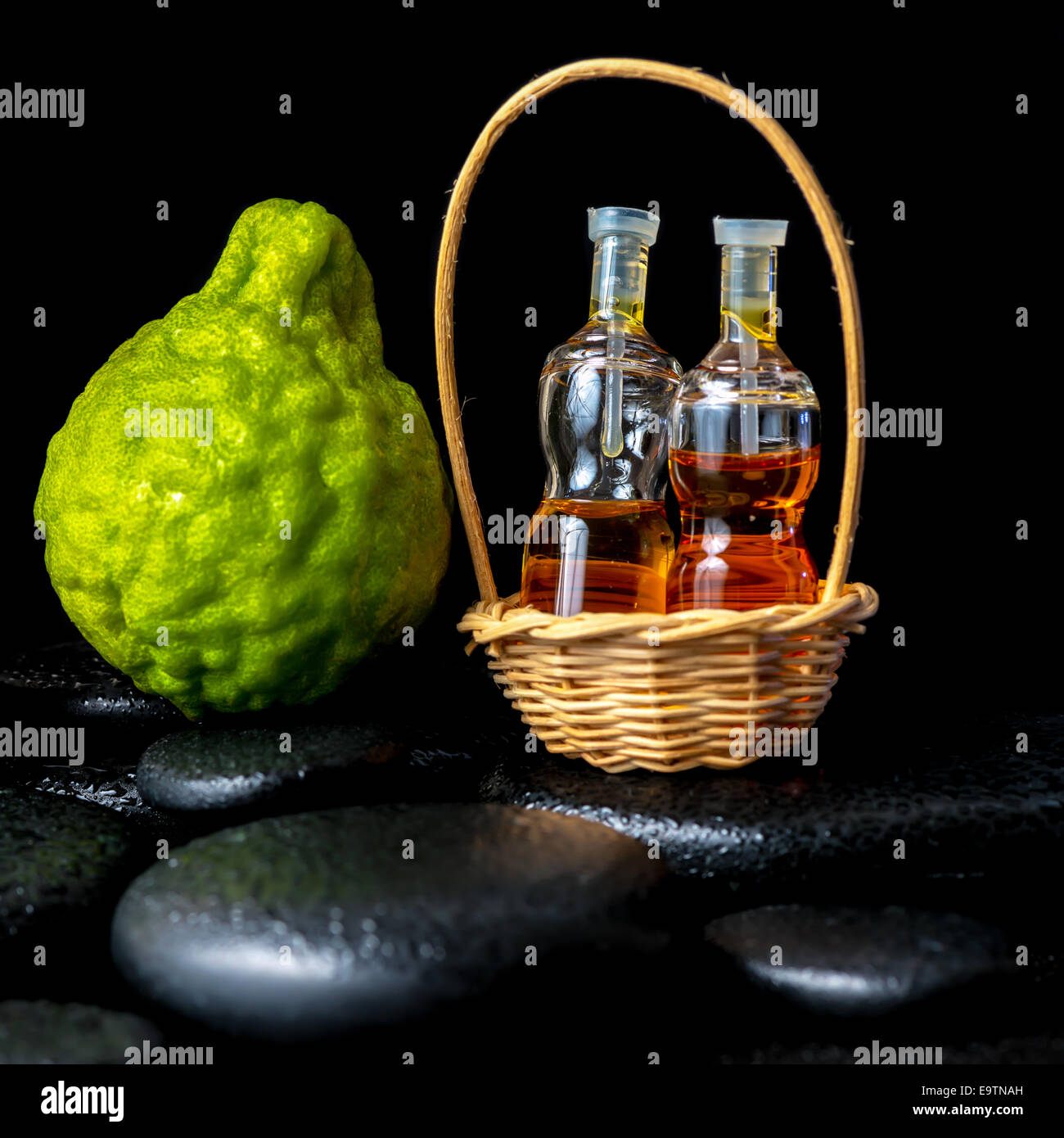 Aromatische Spa-Konzept von Bergamotte Obst und Flaschen ätherisches Öl im Korb auf Zen schwarzen Basaltsteinen mit dem Tau, Nahaufnahme Stockfoto