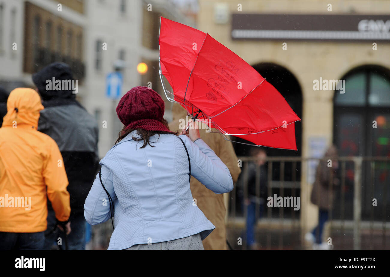 Eine Frau kämpft mit ihrem roten 'Keep Calm and Carry On' Schirm an Brighton Strandpromenade bei stürmischem Wetter Stockfoto