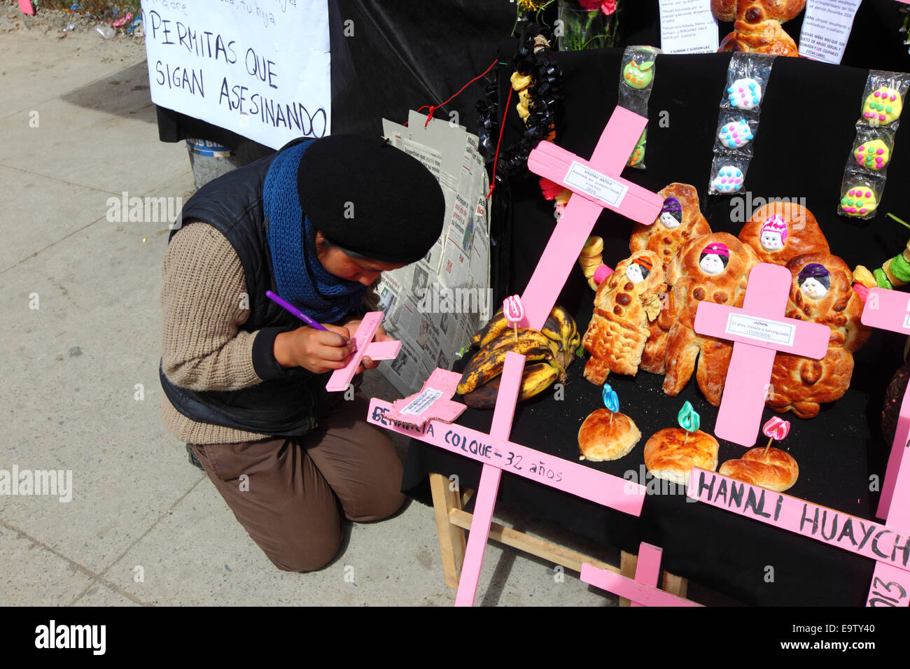 EL ALTO, Bolivien, 2. November 2014. Eine Mädchen schreibt den Namen eines Opfers des Frauenmorde auf einem rosa Kreuz während der Vorbereitung eines typischen Altar oder Mesa für die Todos Santos-Festival. Diese Altäre sind gebaut, um die Seelen von geliebten Menschen begrüßen, die es geglaubt wird, Rückkehr zur Erde am 1. November, um ihre Familien zu besuchen. Zunehmend wird das Festival auch eingesetzt, um Opfer von Verbrechen und Gewalt zu markieren. Laut einem Bericht der WHO im Januar 2013 ist Bolivien das Land mit der höchsten Rate der Gewalt gegen Frauen in Lateinamerika. Bildnachweis: James Brunker / Alamy Live News Stockfoto