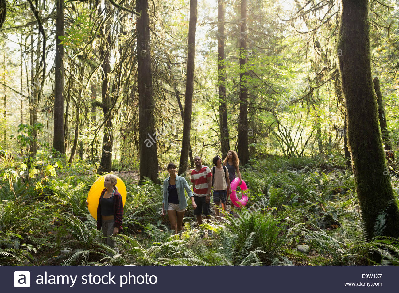 Freunde mit aufblasbaren Ringen Wandern in Wäldern Stockfoto