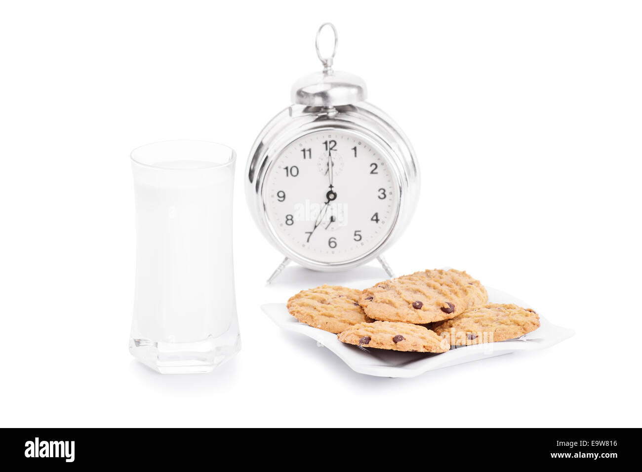 Nahaufnahme von Chocolate Chip Cookies auf einer Servierplatte mit einem Glas Milch und Wecker, auf weißem Hintergrund. Meine morgendlichen und abendlichen Snack. Stockfoto