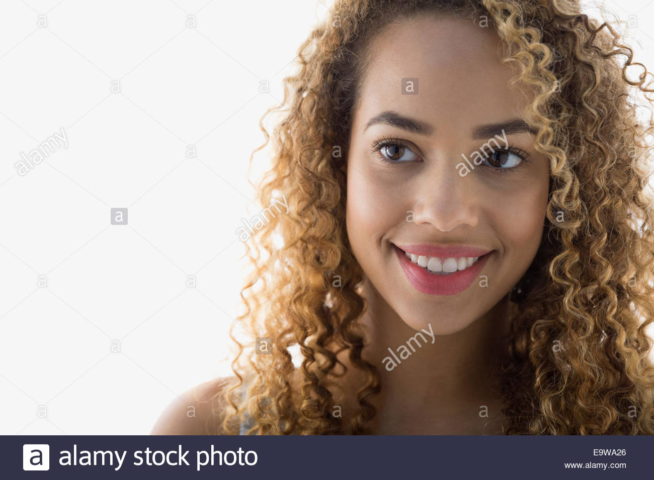 Lächelnde Frau mit lockigem Haar wegschauen Stockfoto