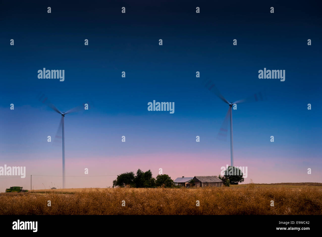 Windpark und Haus - Windkraftanlagen Spinnen auf dem Feld in der Dämmerung. Stockfoto