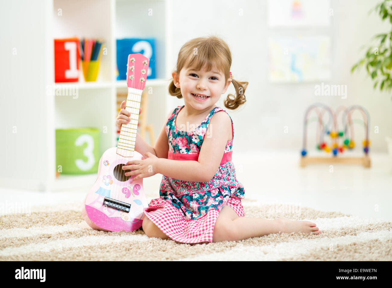 kleines Mädchen mit Gitarre Spielzeug Geschenk Stockfoto