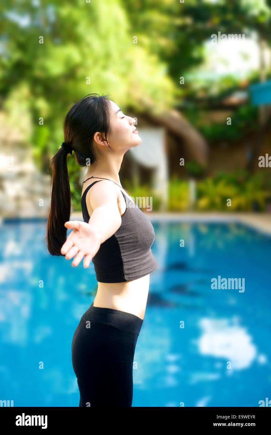 Asiatin offenen Armen in Fitness Outfit relaxen am pool Stockfoto
