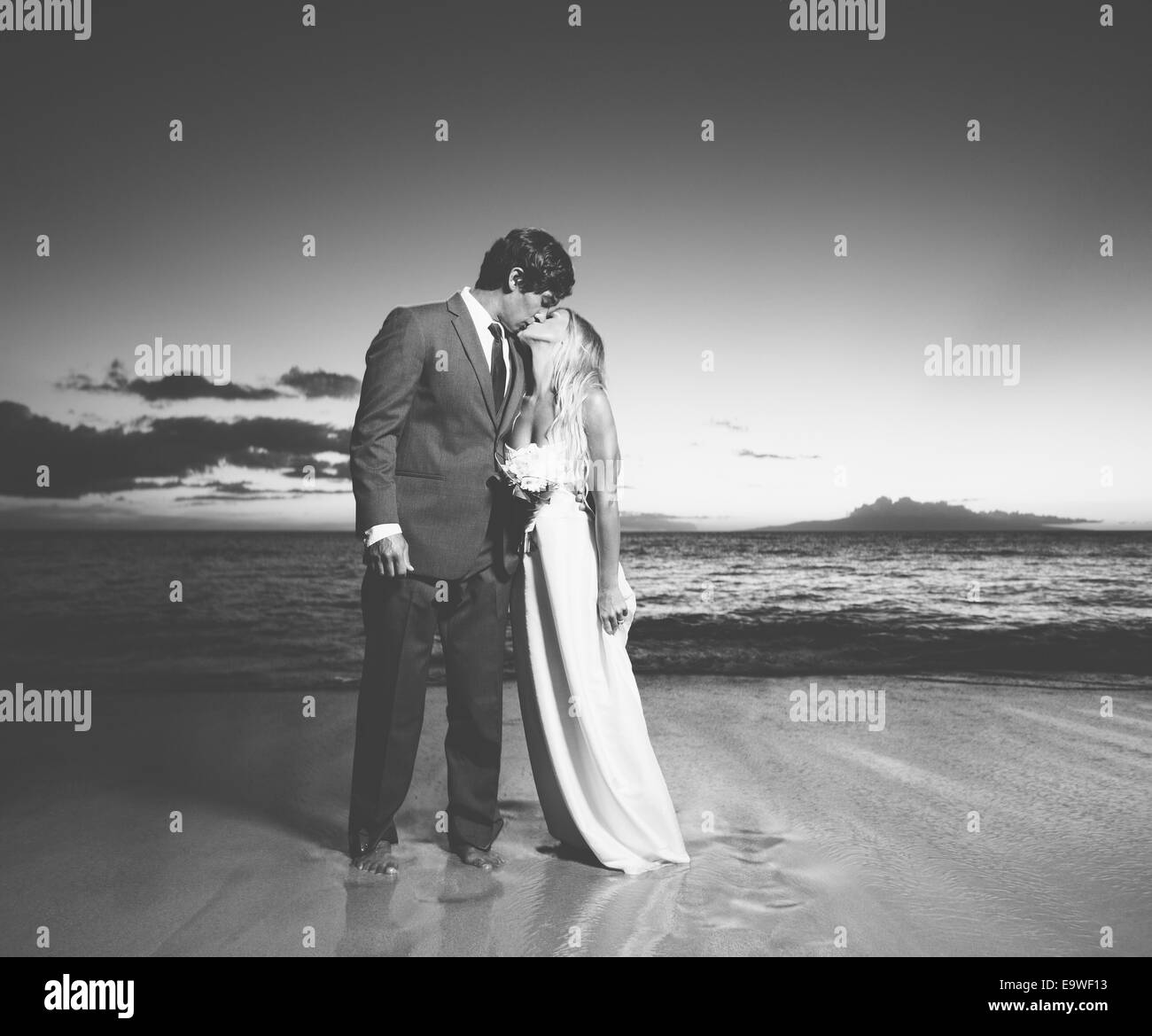 Schöne Hochzeitspaar, Braut und Bräutigam küssen am Strand bei Sonnenuntergang. Schwarz / weiß Foto Stockfoto