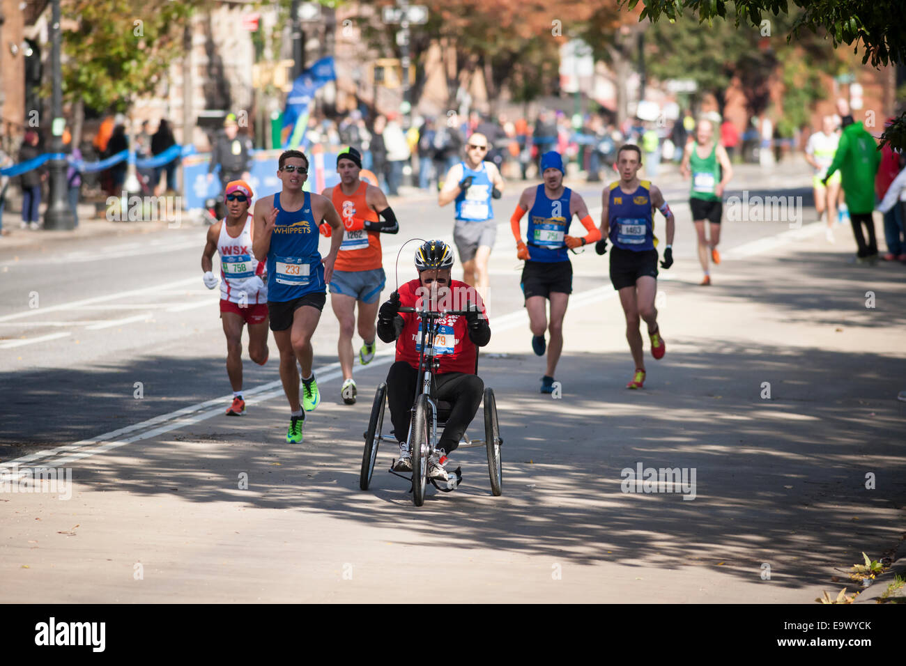 Läufer, einschließlich einen Rollstuhl Teilnehmer durchlaufen Harlem in New York City Marathon Stockfoto