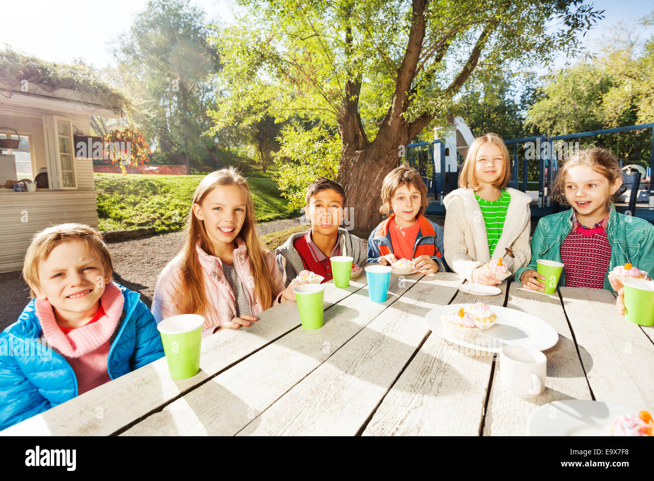 Glückliche Gruppe von Kindern am Tisch draußen sitzen Stockfoto