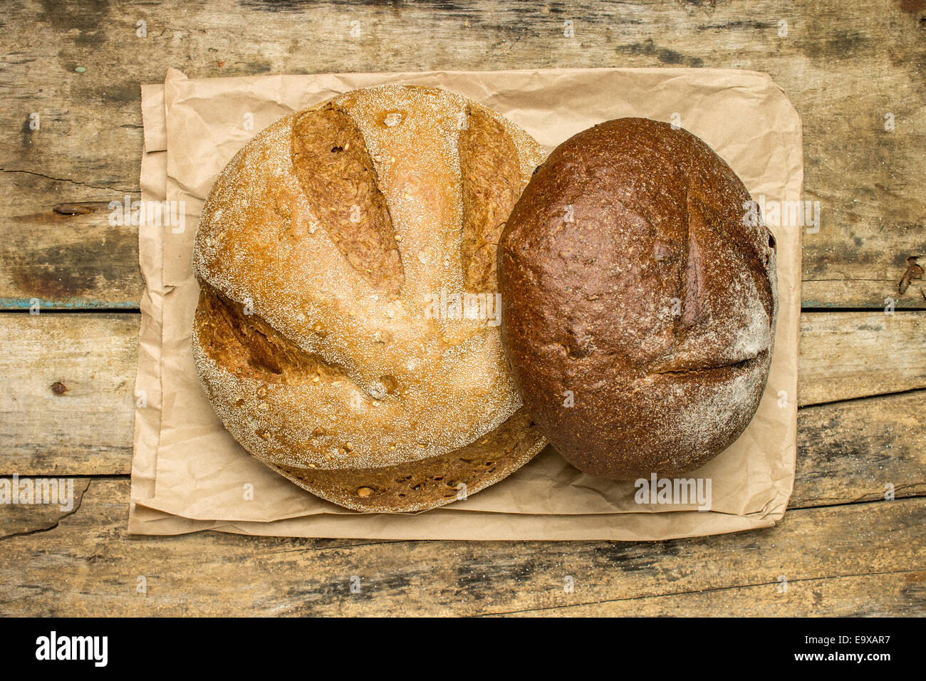 Brote von verschiedenen Arten von Brot auf Holz Hintergrund mit Papiertüte. Ansicht von oben Stockfoto