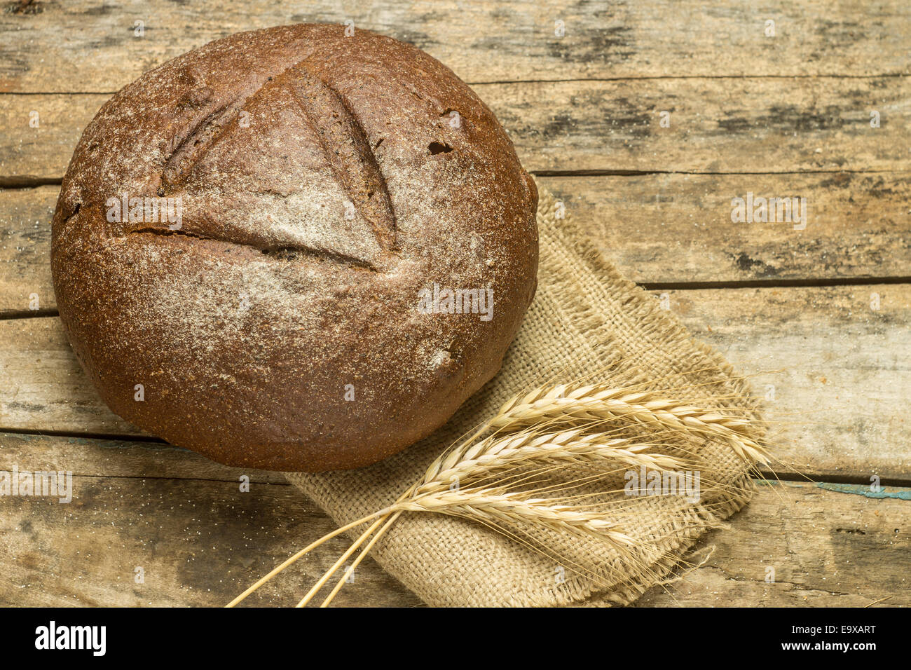 Laib Brot mit Ähren auf hölzernen Hintergrund Stockfoto