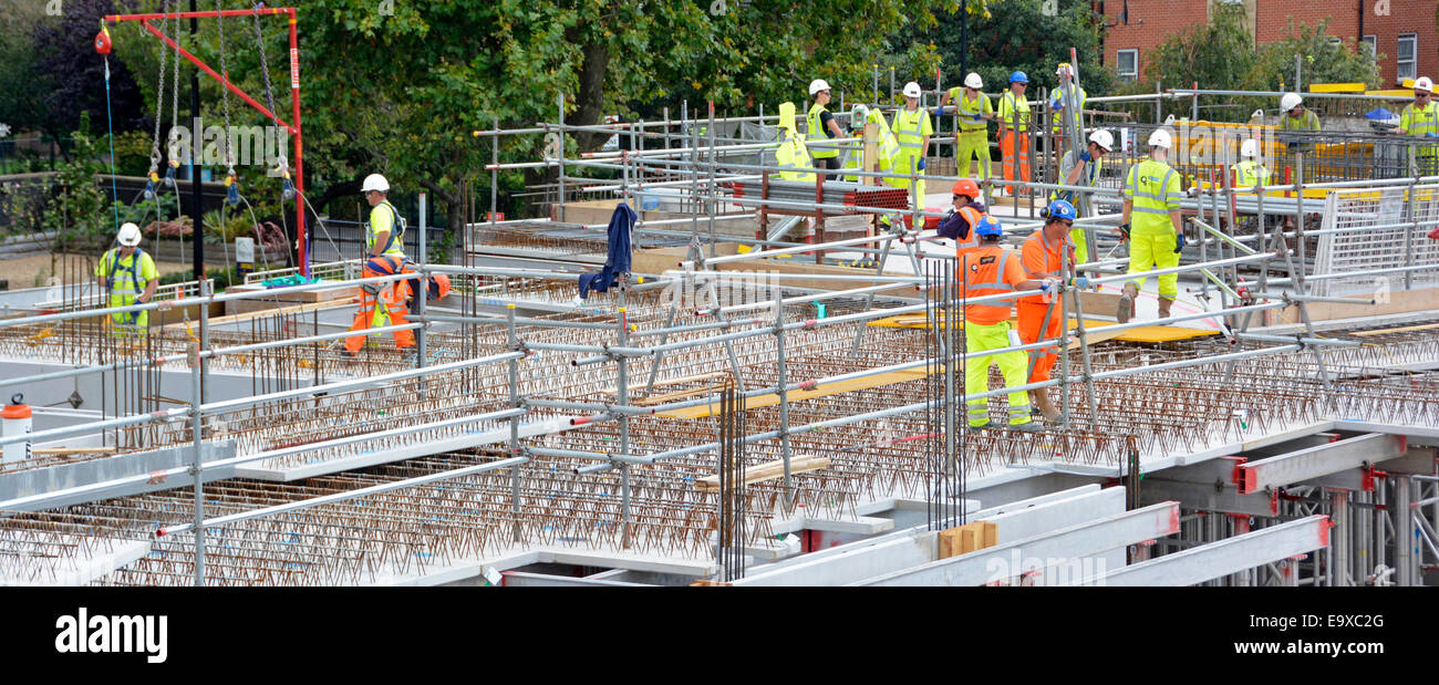 Arbeiter beschäftigt Baustelle arbeiten zusammen auf Betonfertigteil Bodenplatte hoch vis Jacke Harthut Sicherheit & rot Tethering Ausrüstung Großbritannien Stockfoto