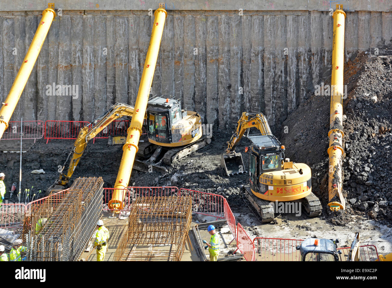 Bauarbeiten Baustelle Arbeit zwischen hydraulischen Rohrstützstreben Cat Bagger Bagger freilegen Beton gestapelt Keller Stützmauer London UK Stockfoto