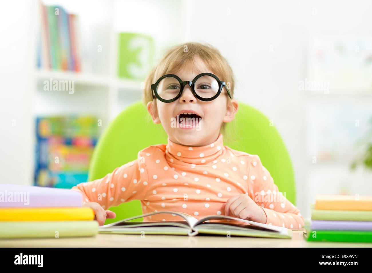 Glückliches Kind lustig Mädchen in Gläsern, die ein Buch in der Grundschule Stockfoto