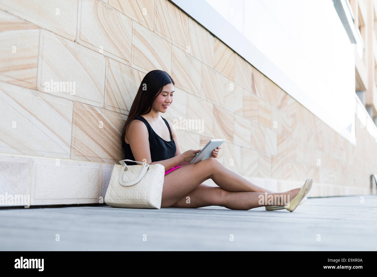 Eine junge Frau, entspannend, während auf einem Tablettgerät Inhalte betrachten Stockfoto