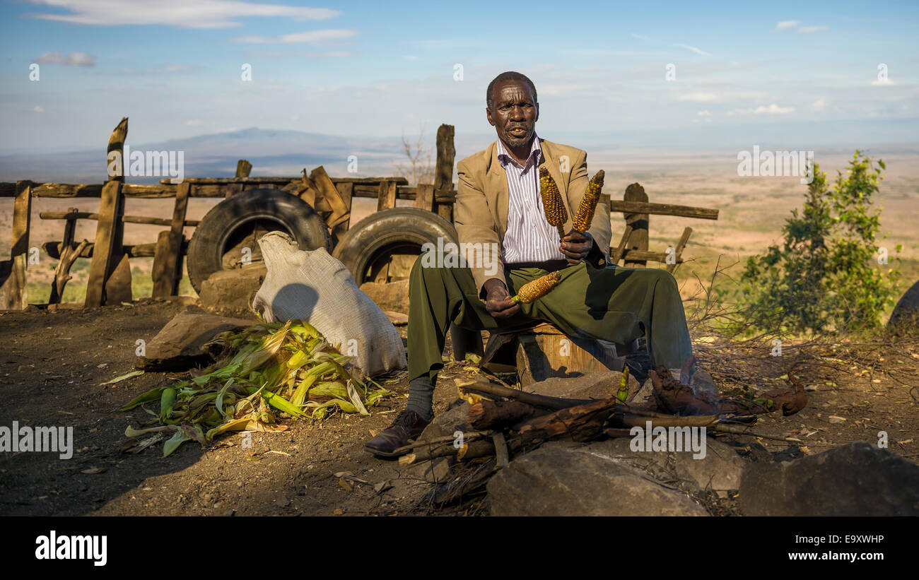Afrikanischer Mann in einem Anzug verkauft Mais an der Kamandura Mai Mahiu Narok-Straße in der Nähe von Great Rift Valley in Kenia Stockfoto