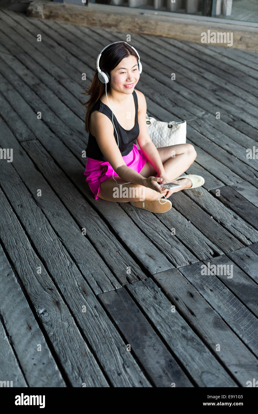 Eine junge asiatische Frau, die mit ihrem mobilen Gerät Stockfoto