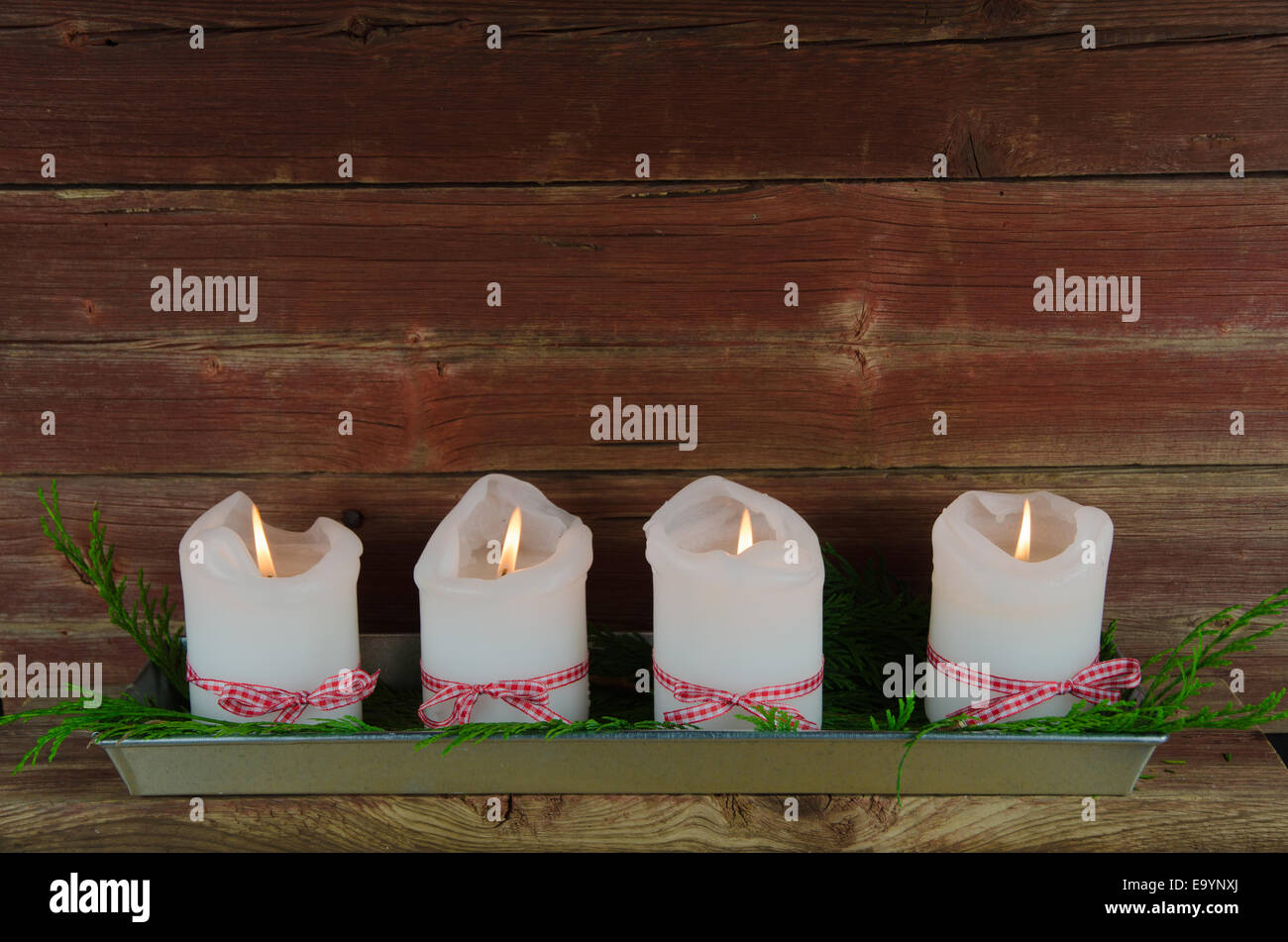 Vier brennende dekoriert Advent Kerzen in einem alten verwitterten roten Wand Stockfoto