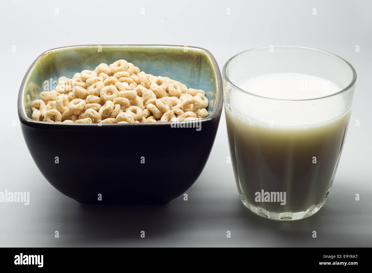 Trockenes Müsli in eine blaue Schale und ein kleines Glas Milch Stockfoto