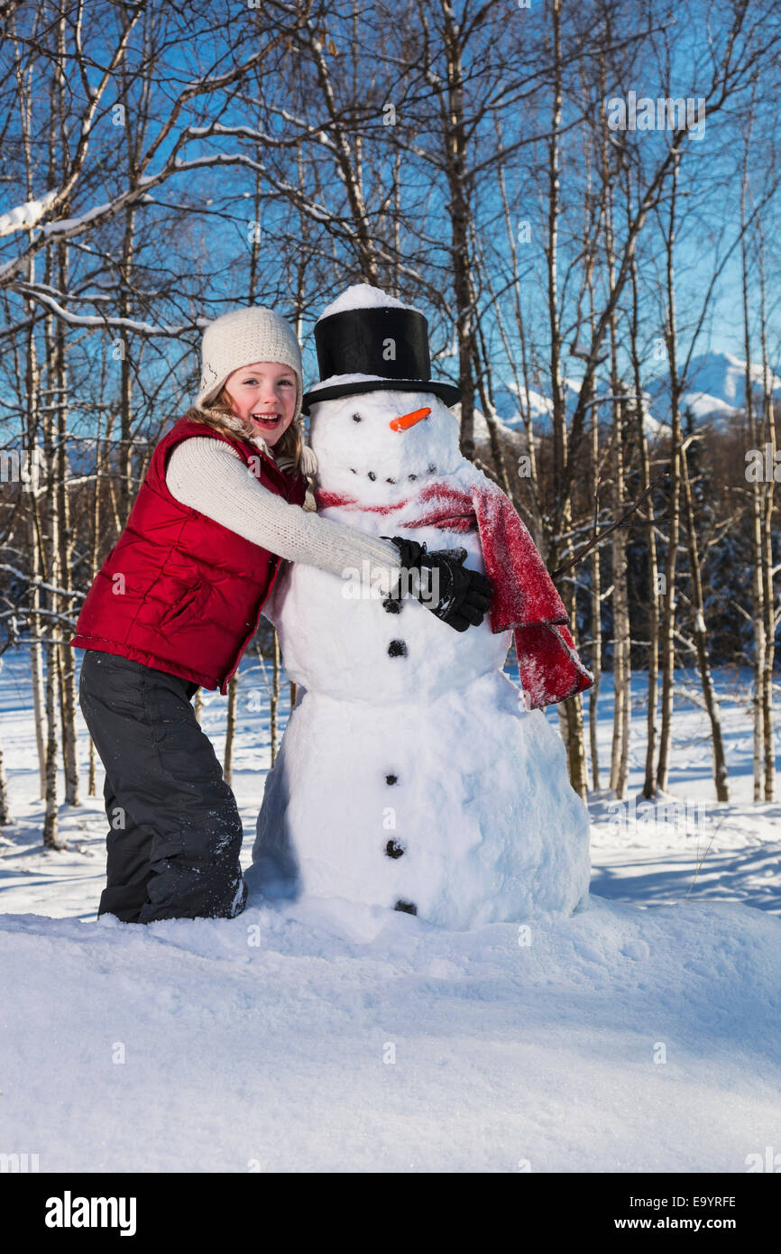 Kaukasische Mädchen umarmt einen Schneemann, Russisch Jack Springs Stadtpark, Anchorage, South Central Alaska Stockfoto