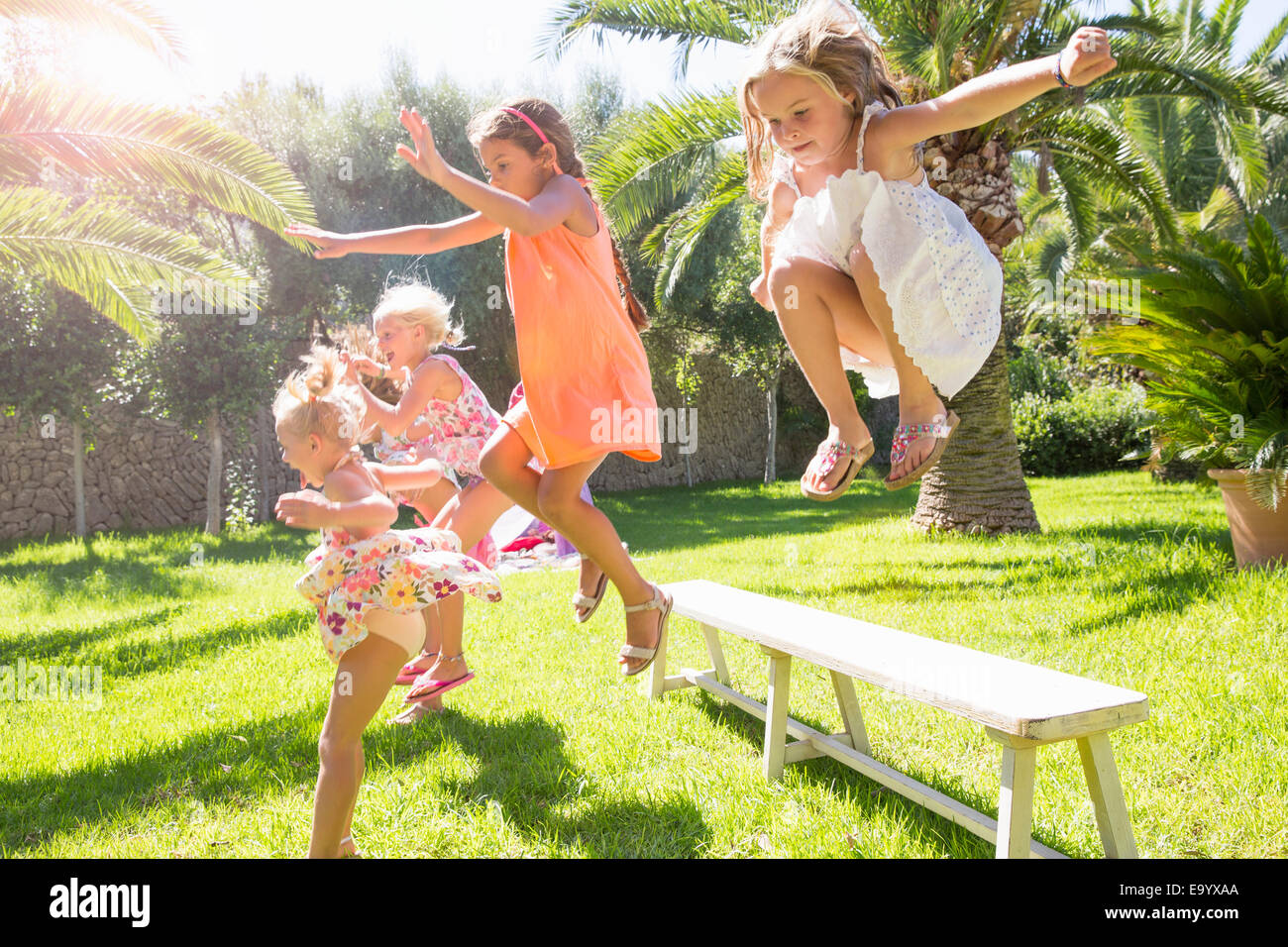 5 energetische Mädchen springen von Gartenbank Stockfoto