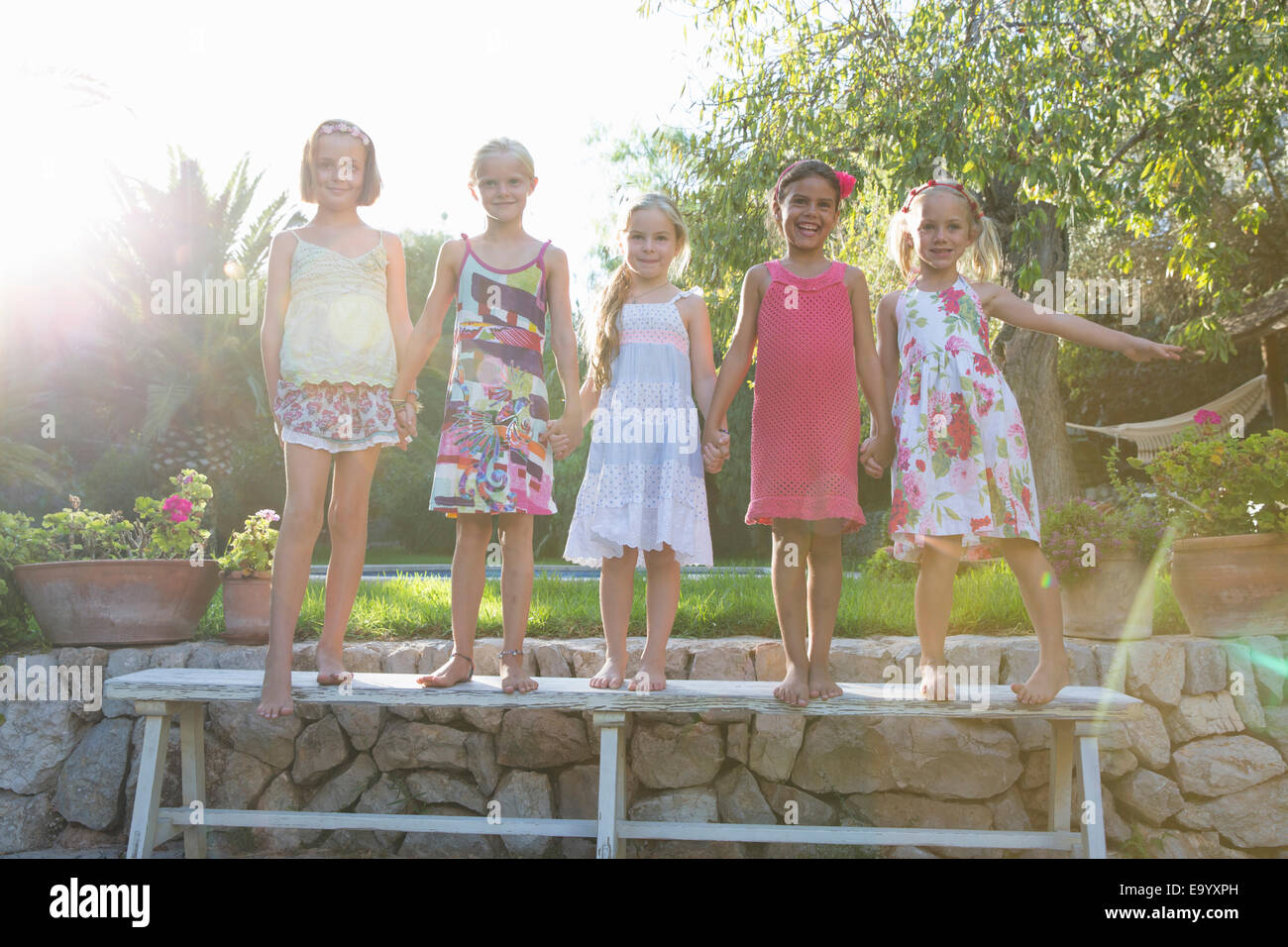 Porträt von fünf Mädchen stehen auf Gartenbank Stockfoto