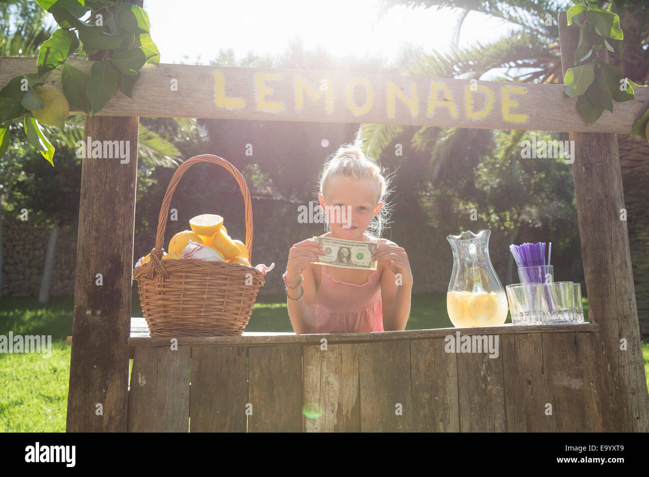 Porträt von Mädchen auf Limonadenstand hochhalten einer Dollarnote Stockfoto