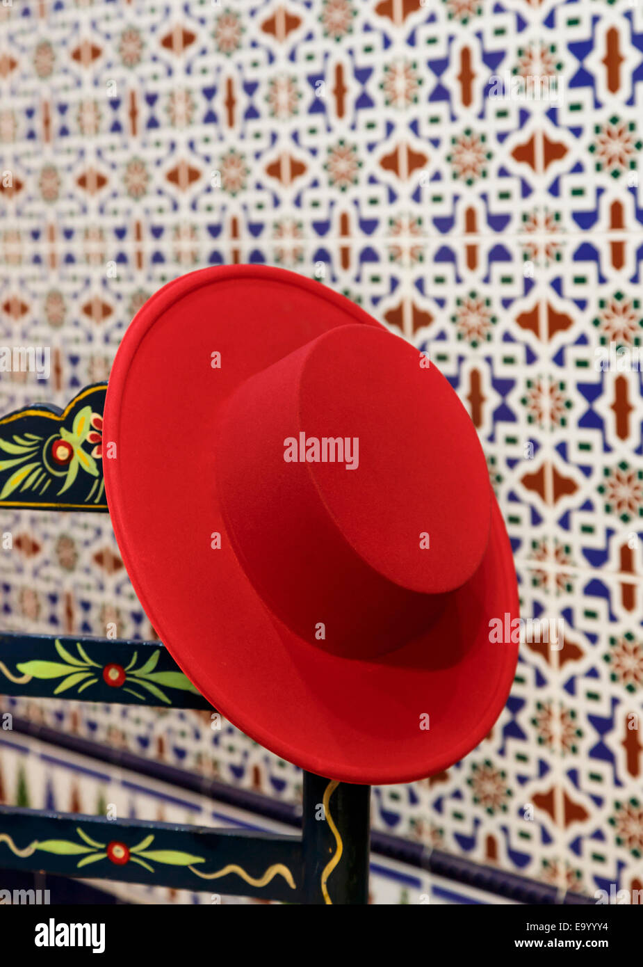 Andalusien, Spanien. Cordovan Red Hut auf Hand lackiert Stuhl.  Eine Frau, einen schwarzen Hut von einem Mann würde ein roter Hut getragen werden. Stockfoto