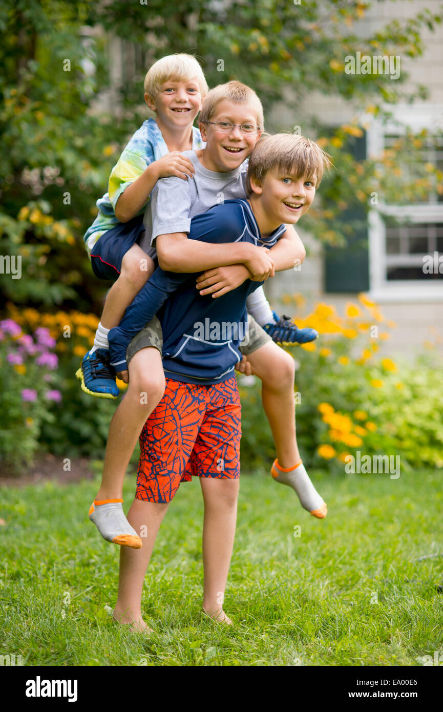 Drei jungen spielen im Garten Huckepack Stockfoto