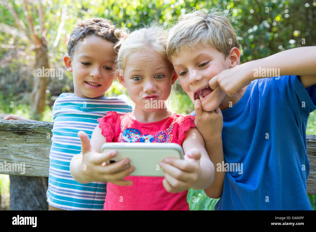 Drei Kinder im Garten nehmen Selfie auf smartphone Stockfoto