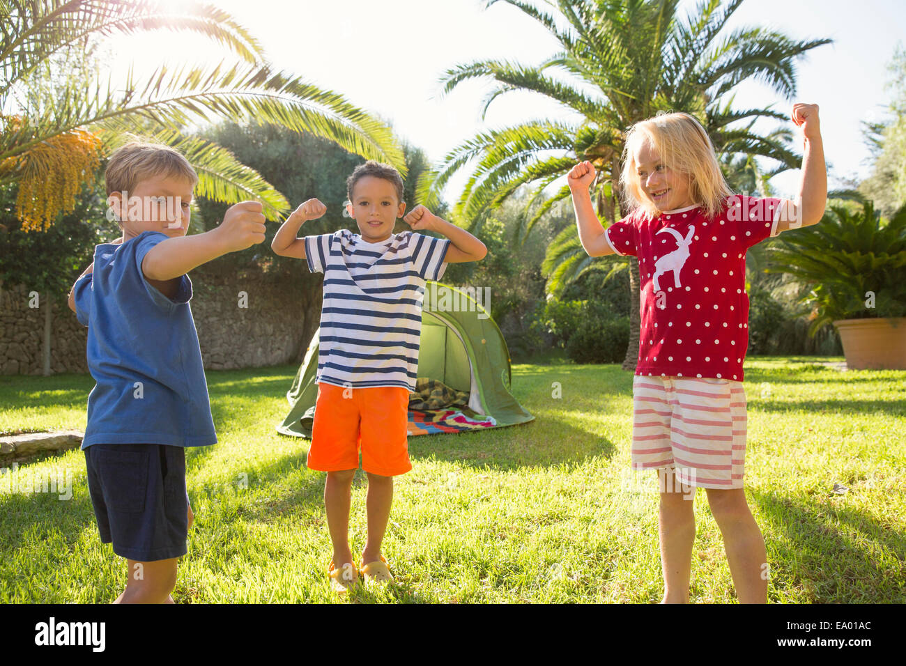 Drei Kinder im Garten, die Muskeln Stockfoto