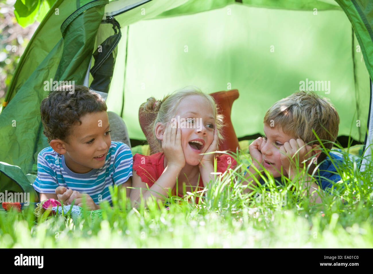 Drei Kinder liegen im Chat bei Gartenzelt Stockfoto