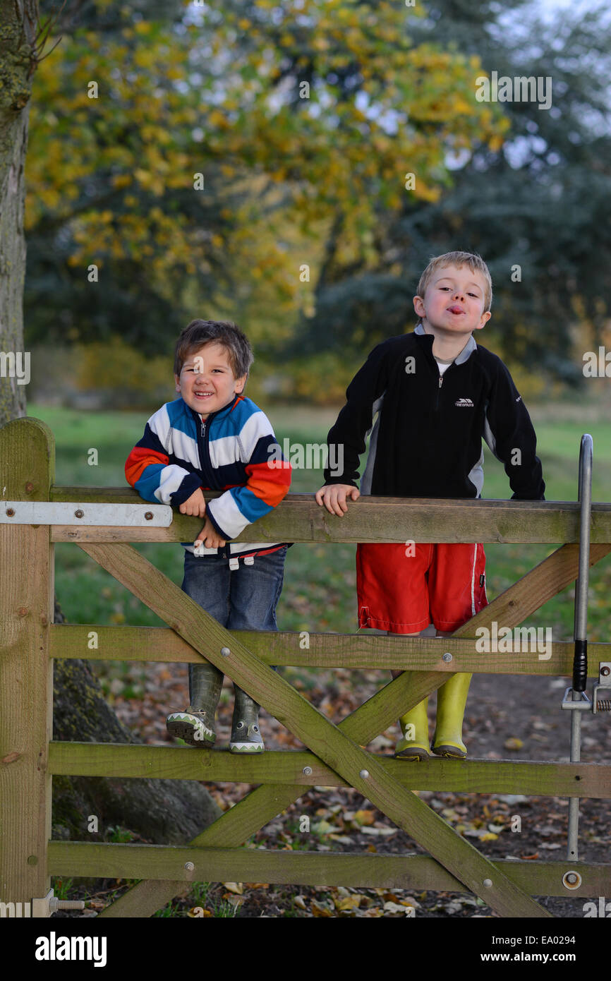 Zwei glückliche freche Kinder jungen Klettern am Holztor Uk Stockfoto