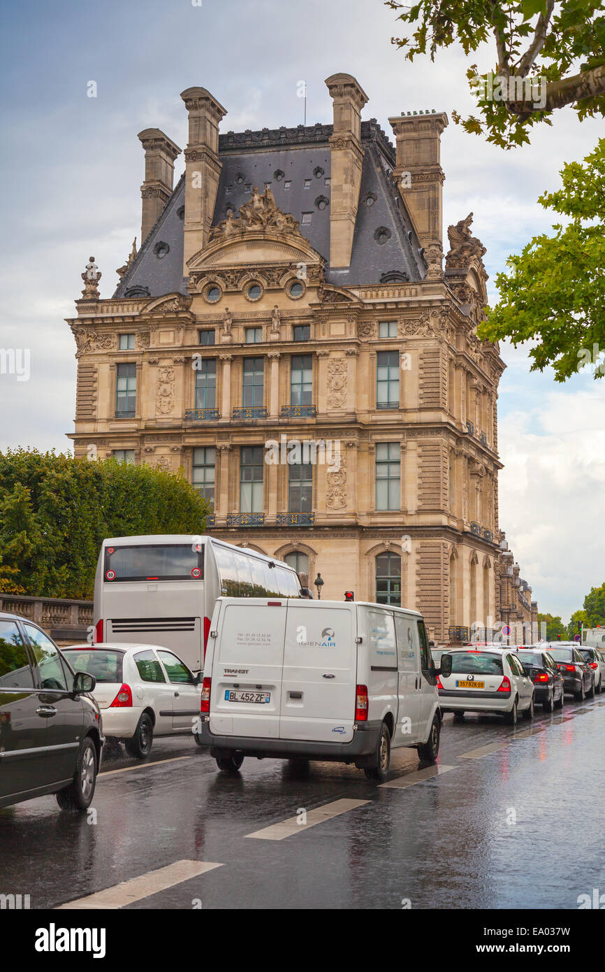 Paris, Frankreich - 7. August 2014: Regentag, französische Autos gehen vorbei an der Fassade des Louvre. Gewöhnliche Straßenansicht aus alten centr Stockfoto