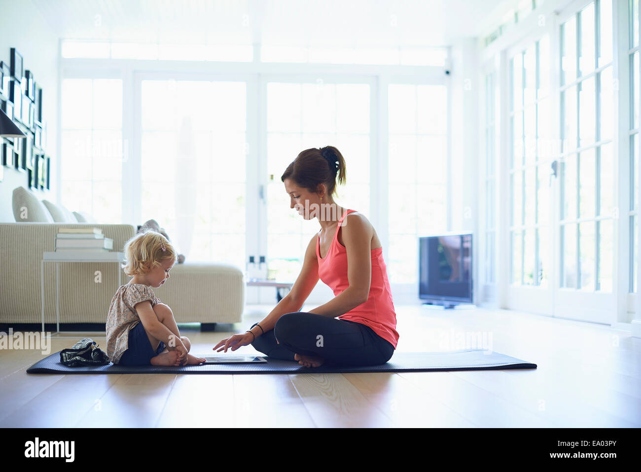 Mitte Erwachsene Mutter und Kleinkind Tochter praktizieren Yoga im Wohnzimmer Stockfoto