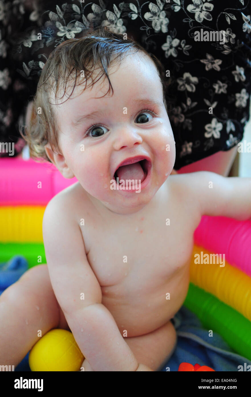 Glückliches Baby in bunten aufblasbaren Pool, ein Bad zu nehmen Stockfoto