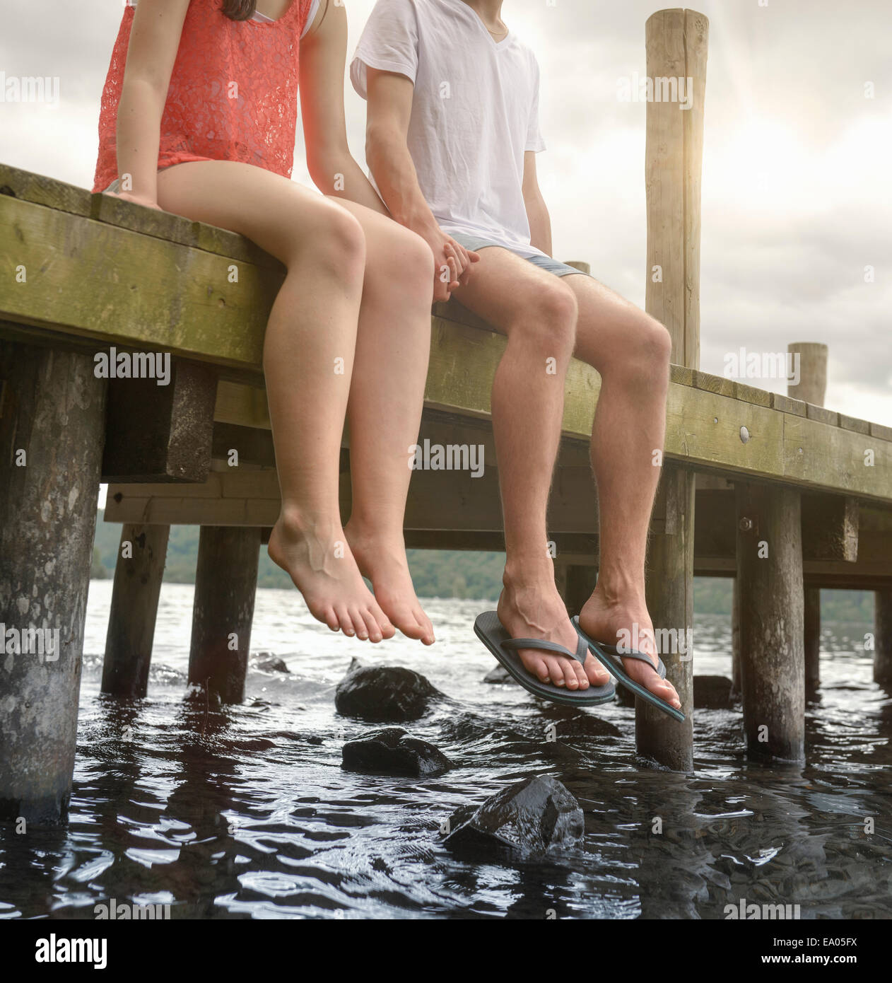 Junges Paar Hand in Hand zusammen und sitzen am Rand der Steg über See Stockfoto